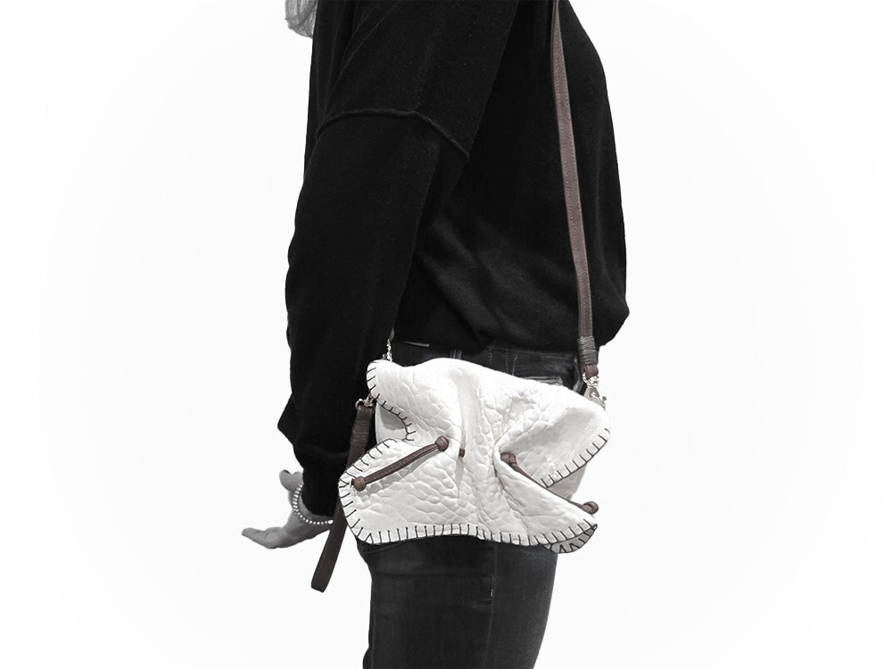 Close-up of the Medium Butterfly Bag's textured leather surface highlighting the subtle embossed logo and intricate