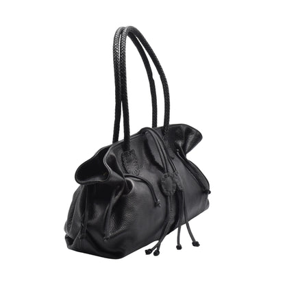 Close-up of gold-tone metal logo plate on textured pebbled leather front flap of Signature Satchel showing fine stitching