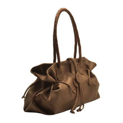 Close-up of textured pink leather handle with gold-tone metal accents on the Signature Satchel.