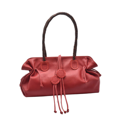 Close-up of the Signature Satchel’s textured pebble leather surface with gold hardware accent and top handle stitching