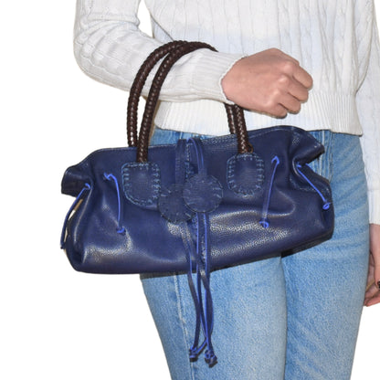 Close-up of the Mini Satchel's textured pebble leather surface with gold-tone zipper pull detail, showcasing craftsmanship