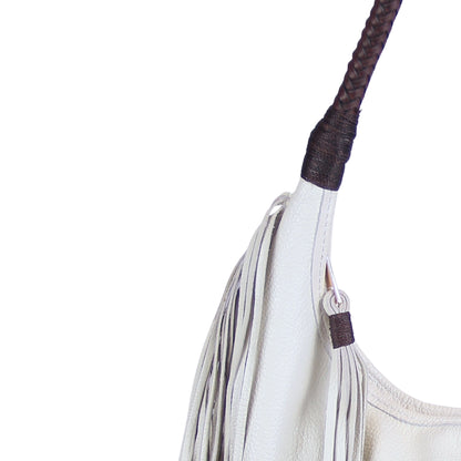 Close-up of the fringed leather texture and metal rivet detailing on the fringe hobo bag's side panel from a diagonal angle.